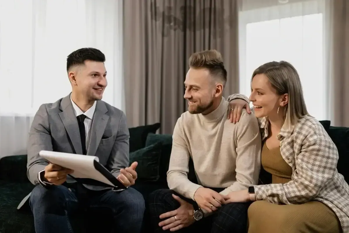Conseiller immobilier présentant un dossier à un couple installé sur un canapé