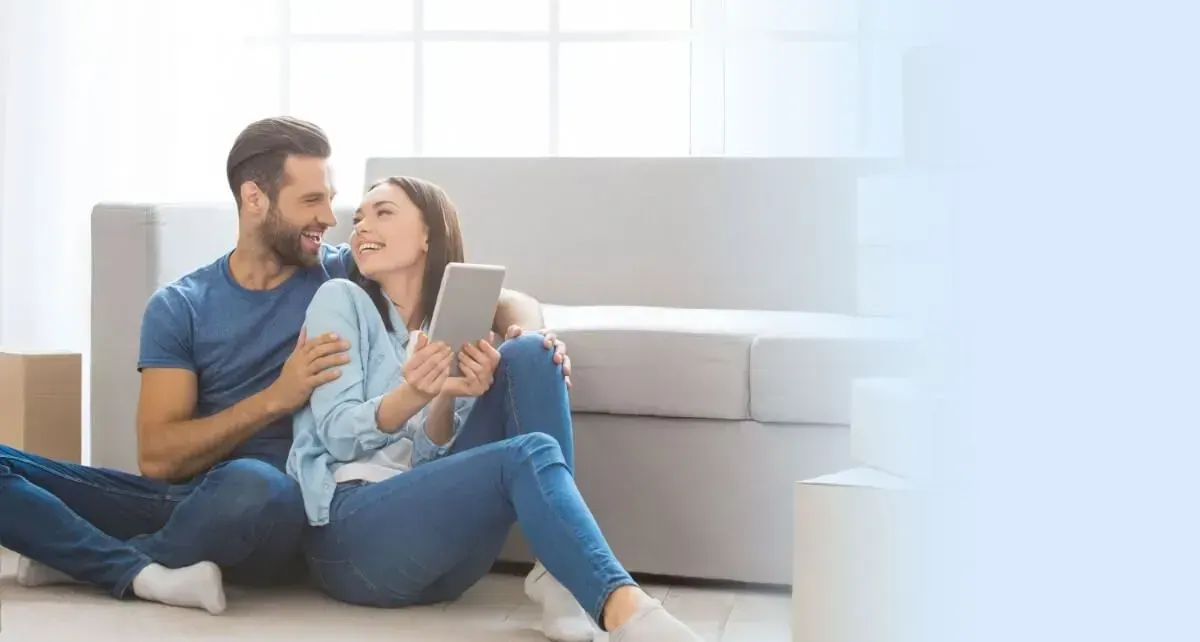 Couple installé sur un canapé, consultant une tablette