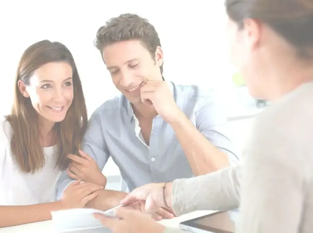 Couple souriant échangeant avec un conseiller devant des documents