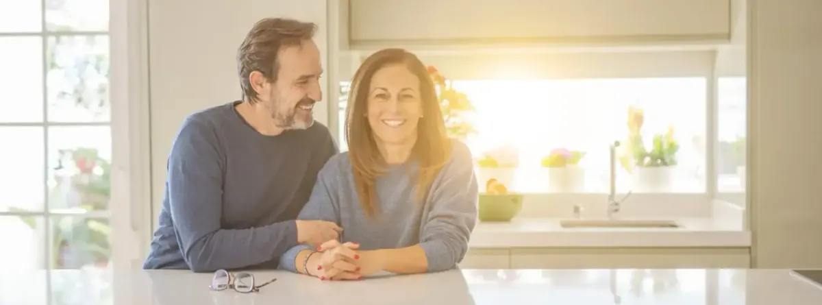 Couple souriant dans sa cuisine, satisfait de son accompagnement