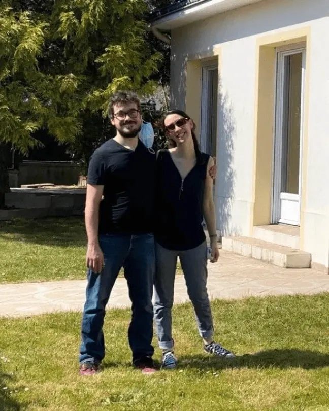 Un couple de clients souriant sur la pelouse devant sa maison